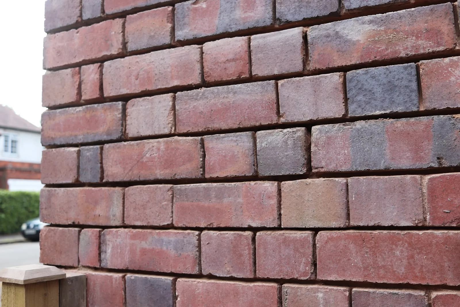A close-up of a freshly repointed brick corner pier, with crisp new mortar joints across mixed red and blue bricks.